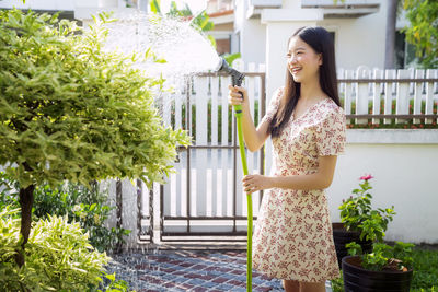 Smiling young woman standing against plants