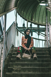 Low angle portrait of girl sitting on staircase