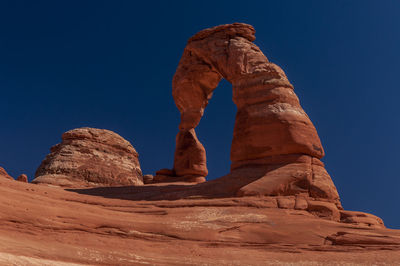 Low angle view of rock formation against clear blue sky