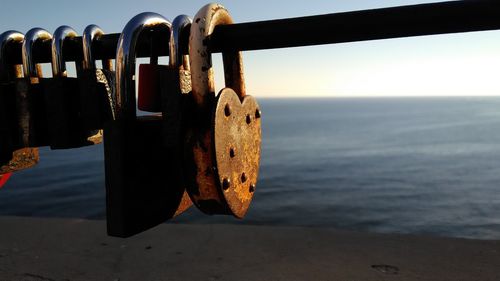 Close-up of padlocks on railing against sea