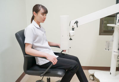 Side view of woman sitting on chair