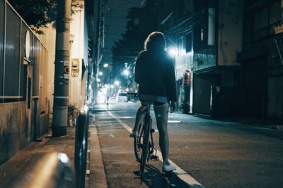 Rear view of woman on bicycle at night