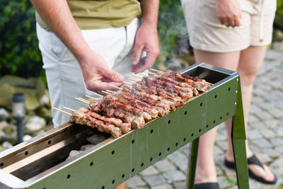 Young man grilling meat kebabs on coals, arrosticini - typical southern italian cuisine, luxurious
