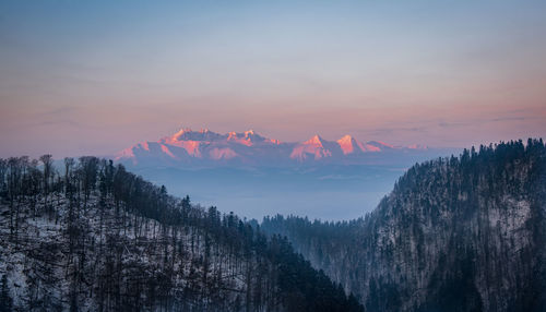 Scenic view of snowcapped mountains against sky during sunset