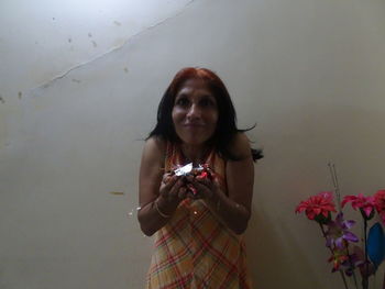 Portrait of young woman standing against white wall