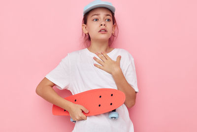 Portrait of cute girl standing against pink background