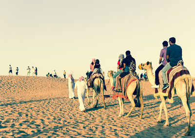 People on beach against clear sky