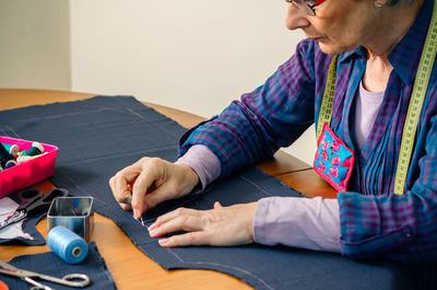 Midsection of woman sewing textile on table