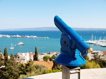 Close-up of a telescope and  blue sea against clear sky