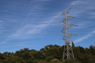 Low angle view of electricity pylon on field against sky