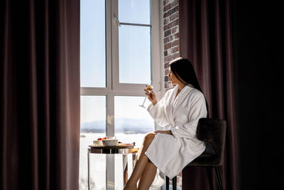 Portrait of young woman looking through window