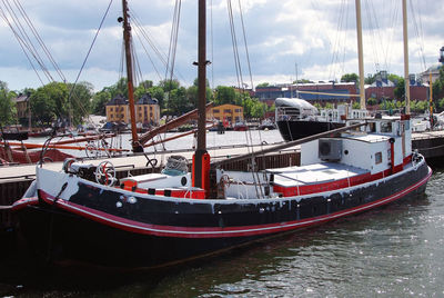 Boats moored at harbor against sky