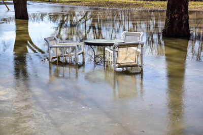 Empty chairs and table in lake during rainy season