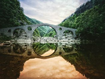 Arch bridge over river against sky