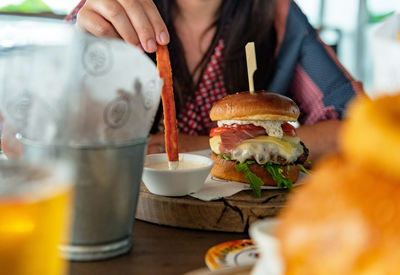 Close-up photo of woman eating delicious hamburger and sweet potato fries in pub