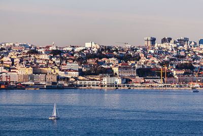 Scenic view of sea by townscape against sky