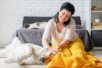 Young woman with dog sitting on sofa at home