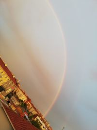 Low angle view of rainbow over buildings against sky