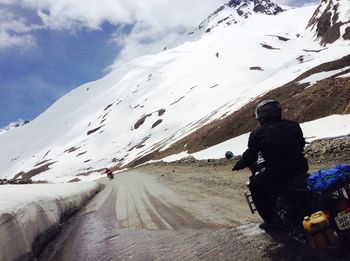 People riding on snowcapped mountain against sky