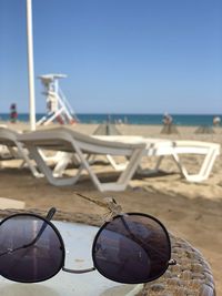 Close-up of sunglasses on beach against clear sky