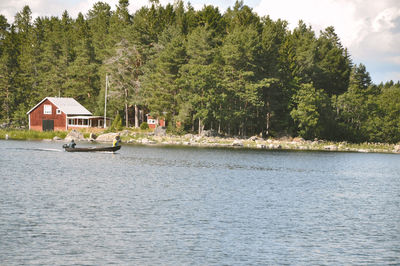 Houses by lake against trees and plants