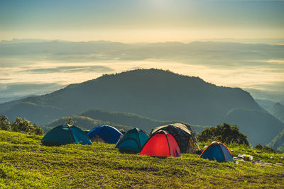 Camping tents on mountain against sky during sunset