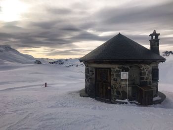 House on snow covered land against sky