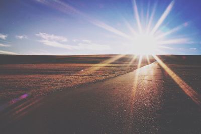 Road amidst agricultural landscape against sky during sunset