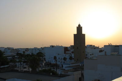 Buildings in city against clear sky during sunset