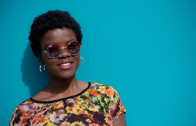 Portrait of smiling young woman standing against blue wall