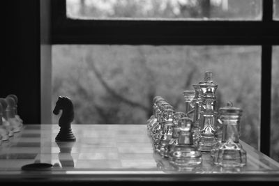 Close-up of chess pieces on board by window