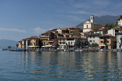 Buildings by sea against sky in town