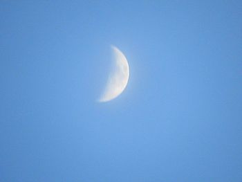 Low angle view of moon against clear blue sky