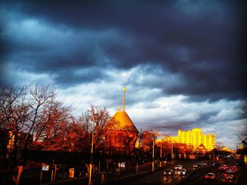 Panoramic view of illuminated city buildings against cloudy sky