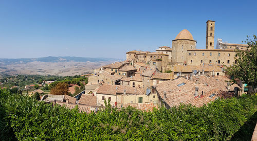 Buildings in city against clear blue sky