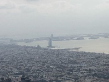 Aerial view of cityscape by sea against sky