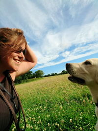 Happy woman face to face with dog on field