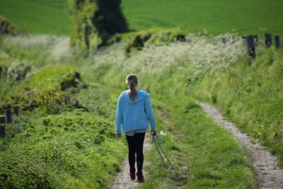 Rear view of girl holding rope while walking on grassy field