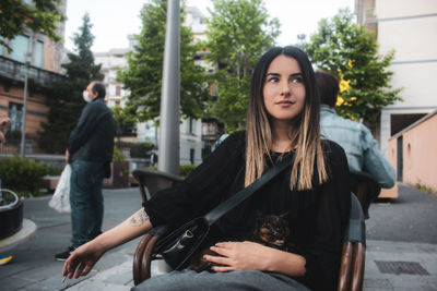 Portrait of beautiful woman sitting in city