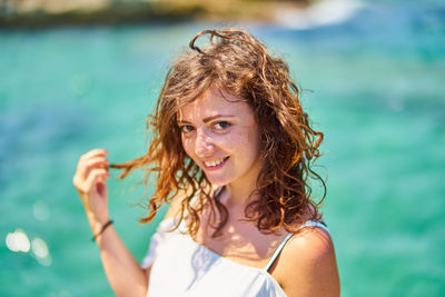 Portrait of smiling young woman against sea