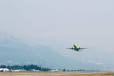 Airplane flying over mountains against sky