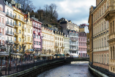 Canal amidst buildings in city against sky