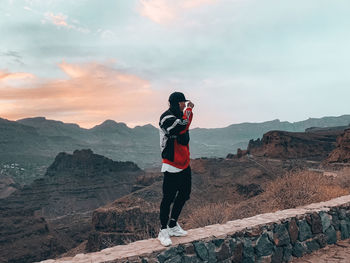 Full length of man standing on rock against sky