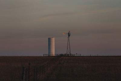 Windmill on field against sky at sunset