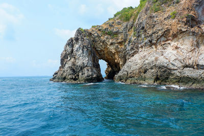 Rock formation in sea against sky