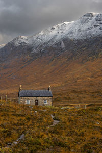 House on snowcapped mountain against sky