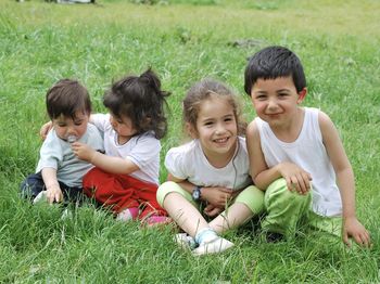 Side view of siblings sitting on grassy field