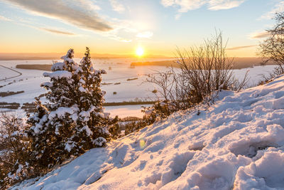Scenic view of snow covered field against sky during sunset