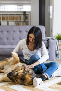 Full length of woman sitting by cat against wall