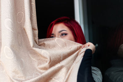 Teen girl behind the curtain, looking outside. young girl alone at home hiding behind window curtain